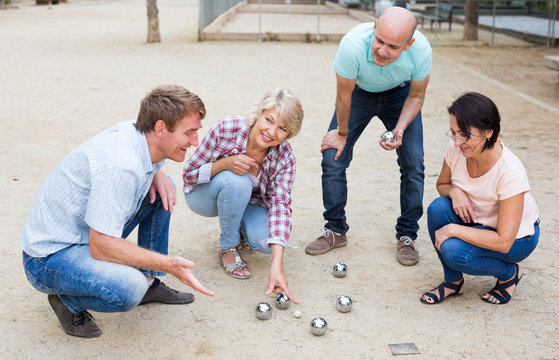 Cheerful males and females playing petanque