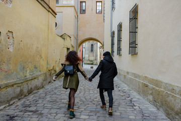Young loving couple dressed in casual style walk at the old city in winter