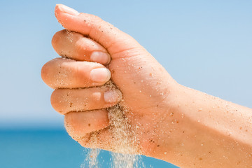 Fototapeta premium hands are pouring sand by the sea