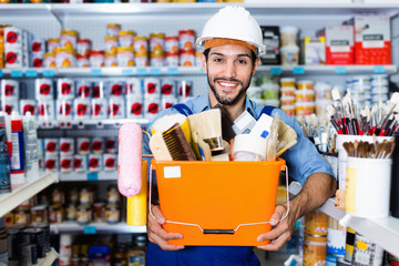 Workman holding basket with picked tools in paint store
