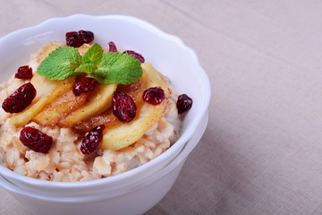 Porridge with caramelized apples and dried cranberries topped with mint