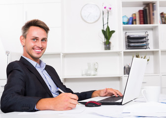Smiling adult business man working on laptop