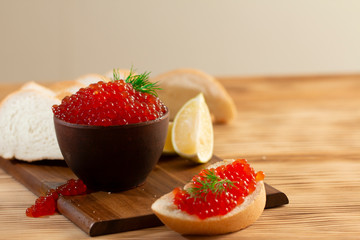 red caviar in a ceramic dish on a wooden background in a rustic style with space for text