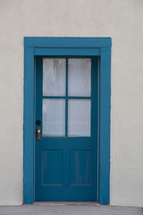 Fototapeta na wymiar Blue door with glass and panels in a stucco wall