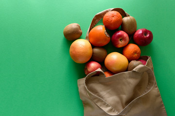 Cotton bag with different fruits on pink background. Ecology pack for free plastic shopping. Top...