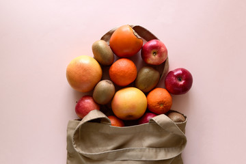 Cotton bag with different fruits on pink background. Ecology pack for free plastic shopping. Top...