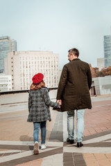 Father walking with his daughter in a red hat