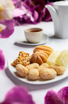 Concept picture of Chinese New Year traditional food with tea pot in background. Variety of cake, pine and other sweet.