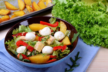 Salad with chicken, roasted potato, mozzarella cheese and red pepper in a bowl