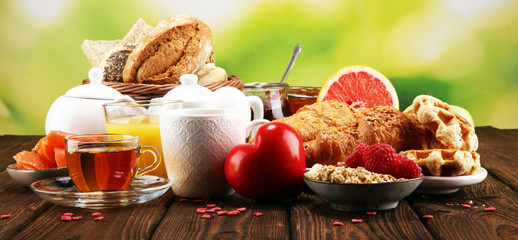 breakfast on table with bread buns, croissants, coffe and juice on valentines day.