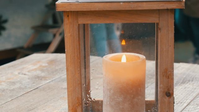 Large wax candle in a stylish wooden candlestick on the table of a street cafe.