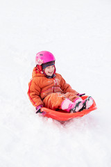 Fototapeta na wymiar A child rides a sled from a hill.