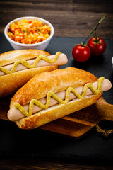 Hot dogs on cutting board on black stone plate