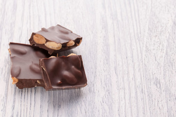 Slices of dark chocolate with nuts on a white wooden table