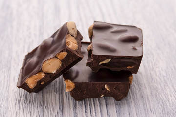 Slices of dark chocolate with nuts on a white wooden table