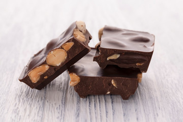 Slices of dark chocolate with nuts on a white wooden table