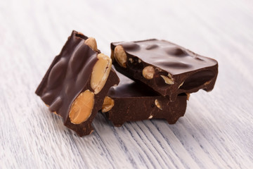 Slices of dark chocolate with nuts on a white wooden table