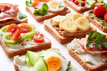 Sandwiches variation with vegetables, fruits, meat, eggs and sweets viewed from above. Variety of bruchetta breads arranged for a tasty and healthy breakfast. 