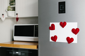 Handmade red felt heart shape magnets on refrigerator door.