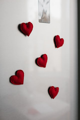 Handmade red felt heart shape magnets on refrigerator door.