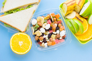 School lunch box. Bread, orange, candies, baby corns, carrot and tomatoes in green plastic container