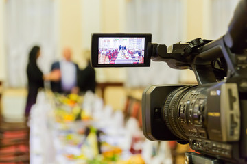 Video shooting at a restaurant at a Banquet. Camcorder with LCD display. People in the hall.