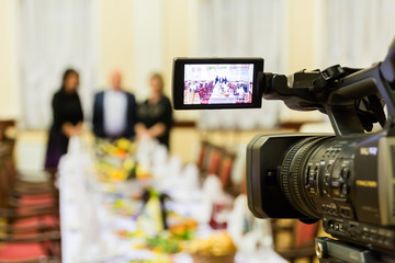 Video shooting at a restaurant at a Banquet. Camcorder with LCD display. People in the hall.