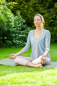 adult woman doing yoga on a green grass