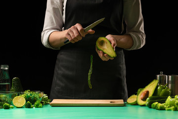 Chef on a black background cuts vegetables for cooking green detox smoothies. Healthy, clean food, weight loss concept, sport
