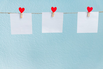 Red Valentine's love hearts pins hanging on natural cord against blue background. Mock up concept for your text