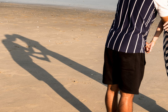 The shadow of a male and female lover who is kissing each other Is a heart shape on the beach On valentine's day