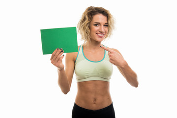 Portrait of beautiful young fit girl pointing green cardboard