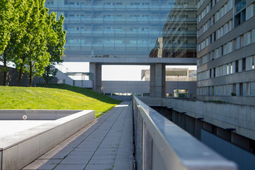 Architectural landscape perspective of buildings exterior and multiple level entrances cladding in glass and concrete columns with above grounds structure footpath in Vienna Austria