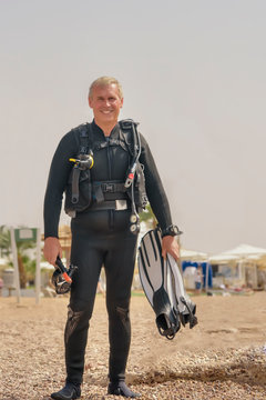 Elderly man is underwater diver with breathing apparatus on the sea beach. Recreational breath-hold diver in basic equipment. A popular water sport and leisure activity
