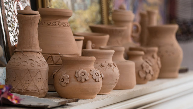 row of clay pots on the shelf, blurred background. children's crafts
