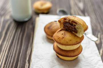 Homemade cupcakes with brown cream and milk on wooden background