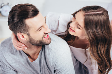 selective focus of young happy lovers hugging and smiling at home