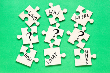 Obraz premium Puzzles with questions Who, Why, Where, How, What, When on the green background.