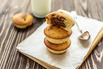 Homemade cupcakes with brown cream and milk on wooden background