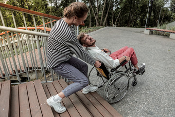 Kind girl helping to lift wheelchair with invalid