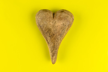 Wooden heart isolated on yellow background with clipping path and copy space on the left and right, view from the top.