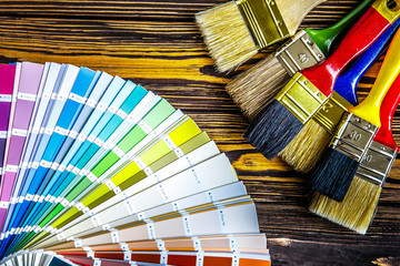 Painter and decorator work table with house project, color swatches, and paint brushes