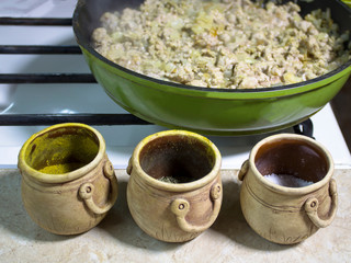 Cooking in the home kitchen. Fry minced meat in a frying pan. Nearby are in clay pots spices.