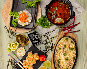 Top view flatlay japanese style business lunch including soup, salad, sushi and main meal at wooden table decorated background.