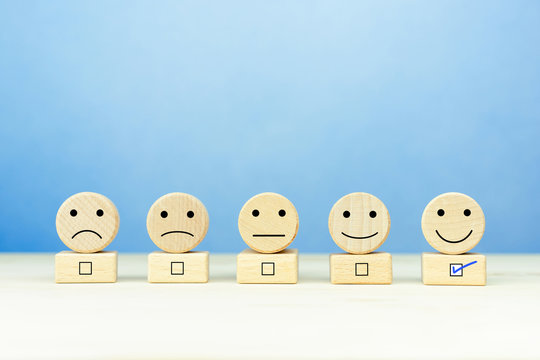 Customer service evaluation and satisfaction survey concepts. Happy face smile face icon on a wooden ball on table