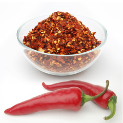 Crushed red hot pepper pile / sun dried chili flakes and seeds in glass jar isolated on white background