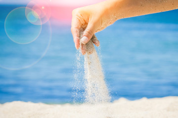 hands are pouring sand by the sea