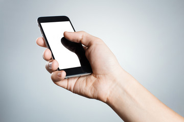 Hand holding black smartphone on gray background