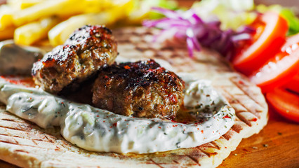 Spicy bifteki, frikadelle or frikkadel meatballs with minced beef and lamb with pita bread,...
