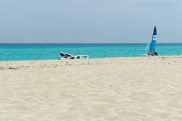 Empty sandy beach with sun loungers. Blue sky ocean.
